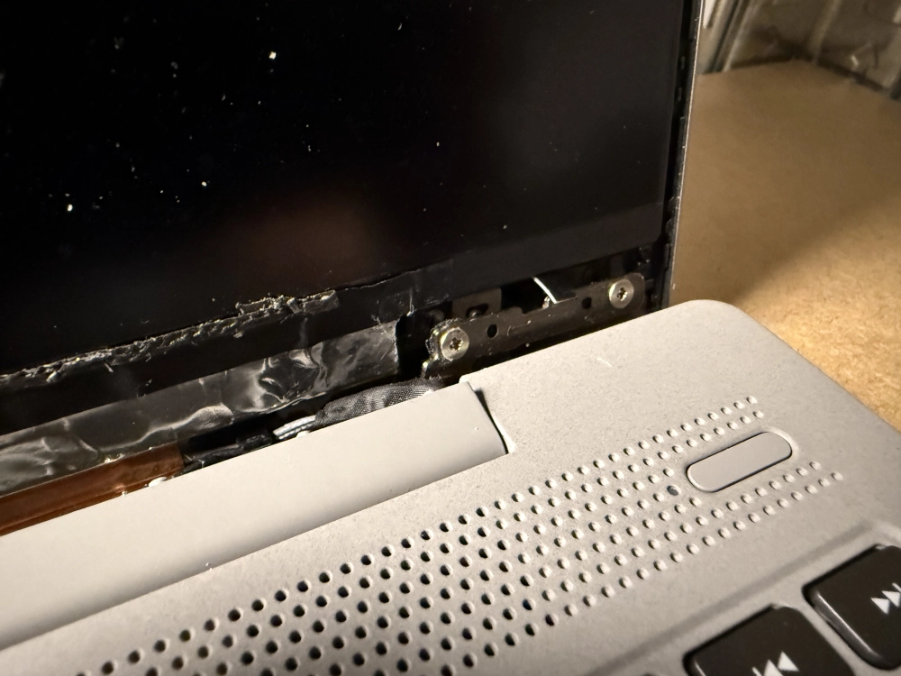 Voor reparatie: scheur in laptop behuizing rond scharnier